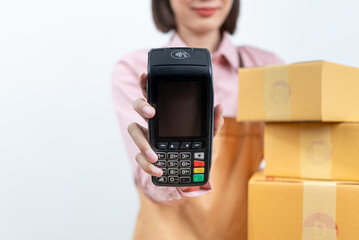 Close up asian woman business owner holding EDC machine or credit card with boxes terminal standing on isolated white background. Shopping online input the serial number of credit card for payment