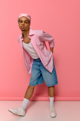 Stylish young man showcases urban fashion against playful pink backdrop