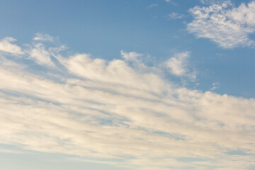 Light cirrus clouds stretching across a calm blue sky, creating a peaceful and serene atmospheric...