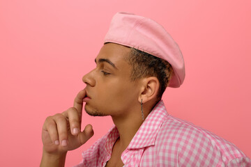 Stylish young man in a pink beret and checkered shirt poses with confidence