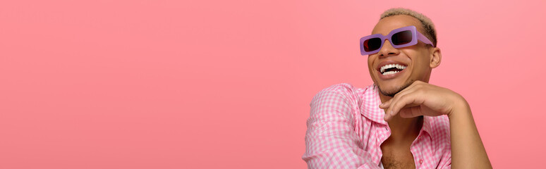 Young man showcases stylish look with dyed hair on a vibrant pink background