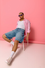 Young african american man showcases vibrant style against a playful pink background