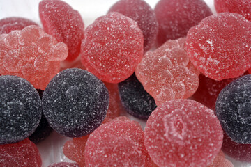 Cherry, red, purple, pink, delicious candies in the form of fruits, currants, grapes, raspberries, blueberries, strawberries. A variety of jelly sweets, all colors of candy are on white background.