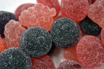 Cherry, red, purple, pink, delicious candies in the form of fruits, currants, grapes, raspberries, blueberries, strawberries. A variety of jelly sweets, all colors of candy are on white background.