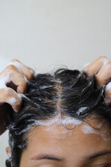 Naklejka premium A woman is taking a shower and washing her hair in the bathroom.