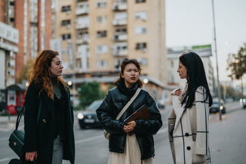 Stylish businesswomen engaged in a discussion on a city street, showcasing collaboration and urban...