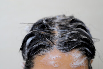 A woman is taking a shower and washing her hair in the bathroom.
