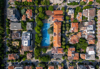 Aerial view of a school or residential block in Varna, Bulgaria. Red rooftops, tree-lined streets, and a blue sports court create a balanced urban landscape