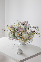 summer wild flowers in white teapot on white background