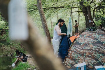 A camping scene featuring multiple people surrounded by tents amidst a green environment....