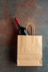 Bottle of red wine in a paper bag on a rusty background.