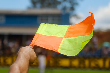 Flag used in football matches with a hand holding the flag, which has the colors red and yellow on...