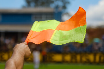 Flag used in football matches with a hand holding the flag, which has the colors red and yellow on...
