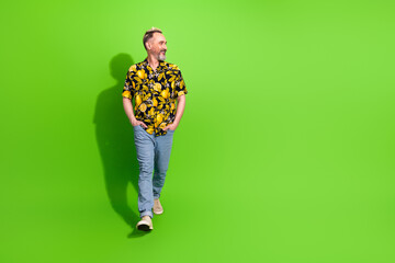 Middle aged man in casual summer clothing smiles against a vibrant green background, embodying...