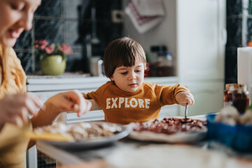 A young child enthusiastically engages in kitchen activities, showcasing learning and creativity in...