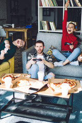 Celebrating victory friends playing game pad eating pizza