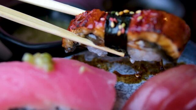 Close up of chefs male hands in gloves cooking sushi rolls with smoked eel in the kitchen. High quality 4k footage