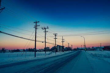 Snowy road and utility poles at sunset