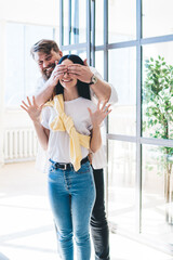 Smiling husband surprising wife with closed eyes