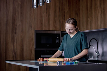 A young woman skillfully prepares fresh dough on a sleek kitchen countertop that looks modern and...