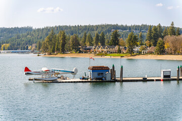 Two floatplanes, or seaplanes wait along a wooden dock at early spring with City Beach and Park...