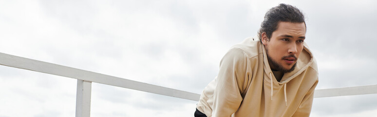 Sporty young man exercising outdoors in a cozy hoodie during overcast weather