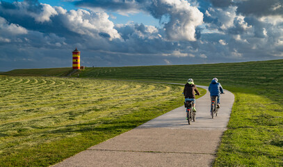 Radfahrer auf dem Weg zum Pilsumer Leuchtturm in Ostfriesland, Deutschland