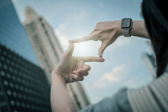 Woman hand gesture focusing on search frame distant city skyline. Concept of vision and clear goals for future, imagining inspiration and defining life path.