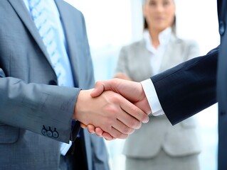 Business deal closes as two executives shake hands, watched by a professional female colleague in a corporate environment.