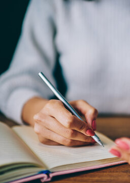 Woman taking notes in notebook while using smartphone