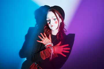 Caucasian teenager girl with creative makeup and red gloves posing with arms crossed against...