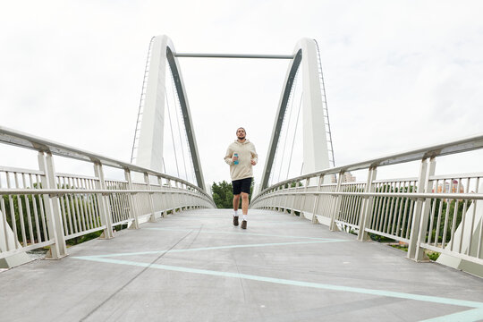 Sporty man exercises on a bridge while enjoying the great outdoors - Powered by Adobe