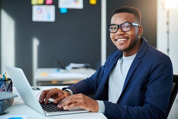 Smiling young businessman working on a laptop in a bright modern office setting with a professional look.