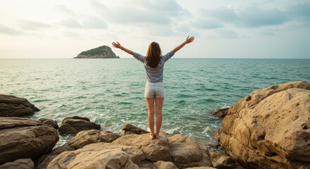Woman Standing on Rocks with Arms Open Enjoying Sea View
