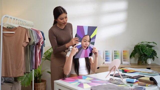 Fashion stylist evaluating personal color tone with fabric fan beside client in bright room
