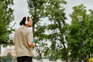 Sporty young man enjoys outdoor workout while listening to music in the park