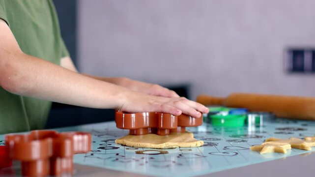 Little boy making cookies using cookie cutters and dough in the kitchen at home.