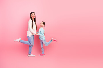 Mother and child in casuals pose playfully against pink background expressing joy, bonding, and...