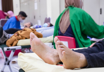 A patient's foots. Several patients on beds, with a healthcare worker conducting an examination, as...