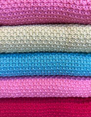 Close-up of neatly folded clothes, showing only visible stripes in a range of harmonized colors....