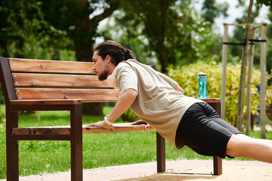 Young man doing push-ups in a sunny park during an outdoor workout