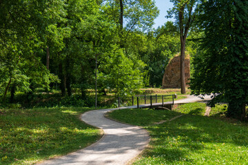 Path with small bridge leading to ruins of Parič water castle in Trebišov city park, surrounded...