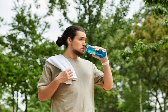 Sporty young man enjoying a workout outdoors while sipping refreshing hydration