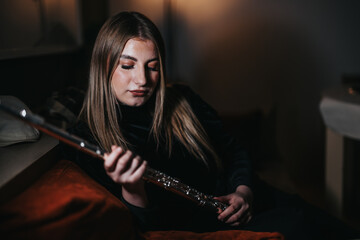 A tranquil portrait of a young woman holding a flute in a softly lit room, depicting a serene and introspective moment.