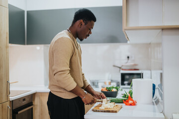 A man slicing vegetables on a cutting board in a bright and organized home kitchen, embodying a...