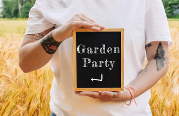 Woman holding a chalkboard with the words Garden Party written on it