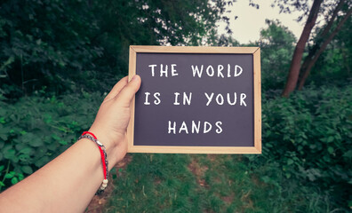 Person holding a sign that says The world is in your hands.