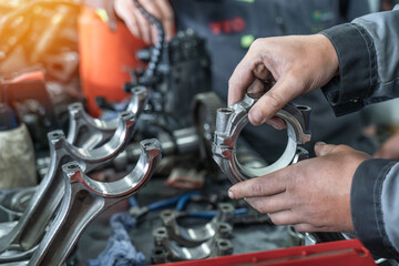 Mechanics assembling engine parts in auto repair shop, showcasing car maintenance, mechanical engineering, metal components, manual labor and professional automotive service.
