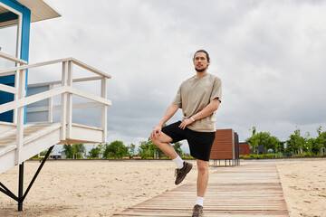 Sporty man exercising outdoors on a sandy pathway near lifeguard station