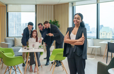 portrait afro creative business woman standing and posing to camera,background blurred multiracial business people gathering and looking at laptop on table